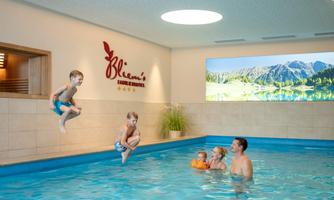 A family hotel with an indoor pool where children play. A boy jumps into the water while adults and another child watch.
