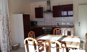 An inviting kitchen with modern furniture and a large dining table. The decor is bright and friendly with plenty of space for cooking and eating.