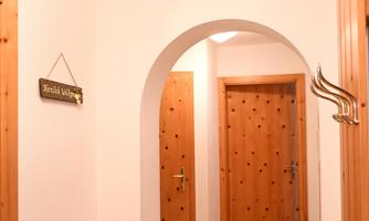 An inviting hallway with an architectural arch. In the background, wooden doors and a wall hook are visible.
