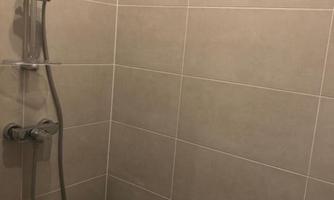 A simple shower area with bright tiles. The shower fixture is modern and functional.