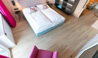 A modern room with a double bed and a cozy seating area. The wooden floors and colorful walls give the space an inviting atmosphere.