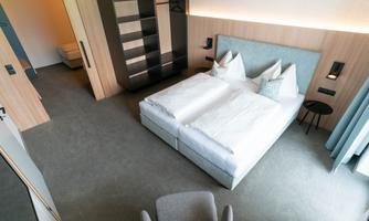 A modern bedroom with a large bed and two pillows. The decor is simple and elegant, with a bright and friendly ambiance.