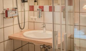 A modern bathroom with a sink on a wooden countertop. The walls are designed with white and red tiled tiles.
