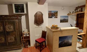 A cozy reception area with a wooden reception desk and an old cupboard. Artwork hangs on the walls, creating an inviting atmosphere.