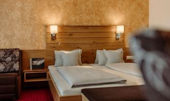 A cozy bedroom with a double bed and bright pillows. The walls are painted in a warm color, and there is a seating area in the corner.