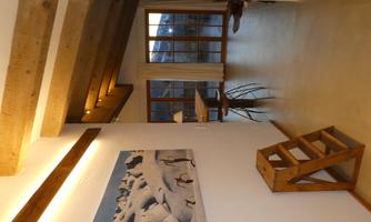 A bright hallway with wooden beams and a painting of penguins in an icy landscape. Large windows provide plenty of daylight.