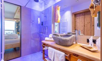 A modern bathroom with a glass shower and an elegant sink. The walls are in soft colors and the lighting creates a relaxing atmosphere.