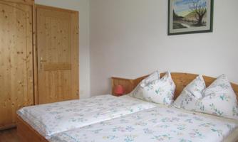 A cozy bedroom with a double bed and wooden furniture. A picture hangs on the wall, and there is a wardrobe.