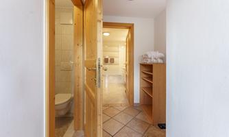 A bright bathroom area with wood details. Towels and a toilet are visible in the background.
