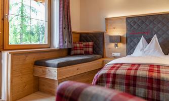 A cozy room with a double bed and a seating area.  
Large windows let in plenty of light and offer a view of nature.