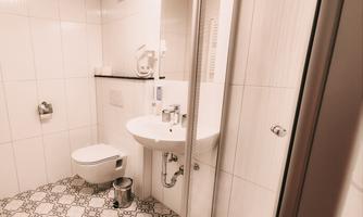 A modern bathroom with a shower, a sink, and a toilet. The floor is adorned with elegant tiles.