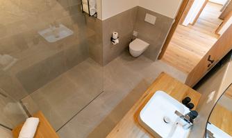 A modern bathroom with a walk-in shower and a wooden vanity. The room is elegantly designed and well-lit.