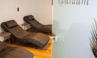 A relaxation room with two comfortable loungers and a modern design. The wooden floor and soft lighting create a relaxing atmosphere.