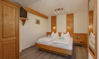 A cozy bedroom with wooden paneling and two beds. The environment is clear and bright, ideal for a relaxing stay.