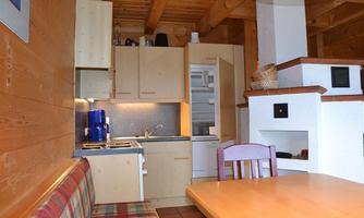 A cozy kitchen with wood paneling and modern furnishings. The room features a dining table and a seating area with a lovely bench.