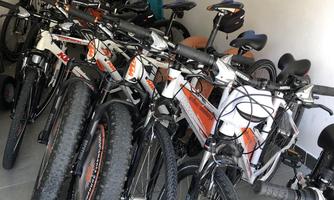 A series of bicycles are standing in a room. In the background, there is a child bike seat.