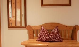 A cozy hallway with a wooden bench and a large mirror. A decorative picture hangs on the wall.