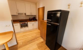 A modern kitchen with high-quality appliances and wooden flooring. The refrigerator is black, and there is plenty of counter space.