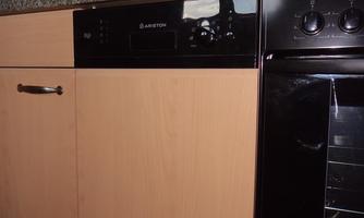 A modern kitchen with wooden cabinets and a granite countertop. An oven and a dishwasher are visible.