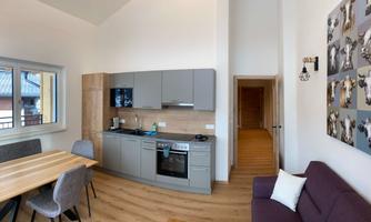 A modern, spacious kitchen with a large dining table and a cozy living room. The interior design is bright and inviting.