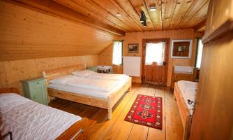 A cozy bedroom with wooden paneling and two beds. The room has large windows and a carpet that radiates warmth.