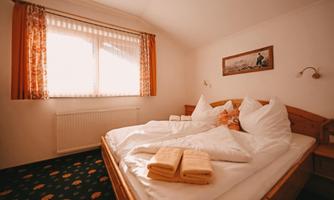 A cozy bedroom with a large bed and fresh towels. The window lets in plenty of light, creating a bright atmosphere.