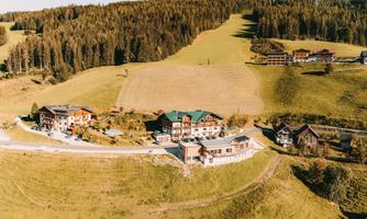 A picturesque landscape with several houses amidst green meadows and forests. The surroundings offer a calm and natural atmosphere.