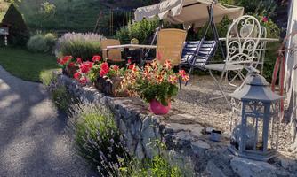 An inviting seating area with blooming flowers and a sunshade. In the background, cozy chairs and a decorative lantern can be seen.