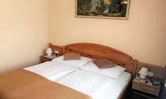 A cozy bedroom with a double bed and a wooden bench. A colorful painting hangs on the wall.