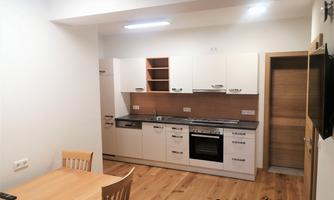 Modern kitchen with wooden surfaces and a bright design. A dining table with chairs complements the living area.