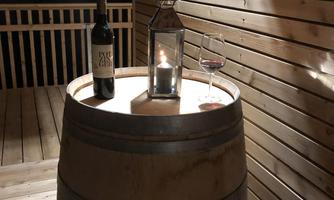 A wooden barrel as a table with a bottle of red wine, a glass, and a lantern. The scene is cozy and casts warm light.