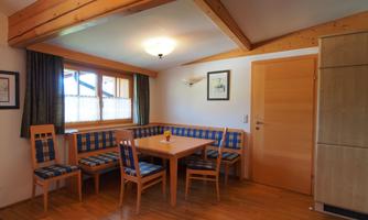 An inviting dining area with a wooden table and comfortable benches. Large windows let in plenty of daylight.