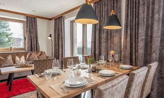 A modern dining room with a wooden chair and elegant table decoration. Soft lighting creates an inviting atmosphere.