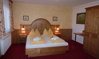 A cozy bedroom with two single beds and yellow cushions. The room has wooden furniture and warm lighting.