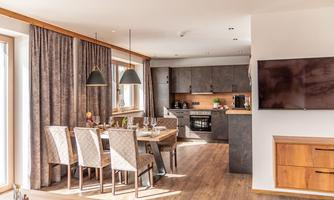 A modern kitchen with a dining area. Large windows let in plenty of light and create an inviting atmosphere.