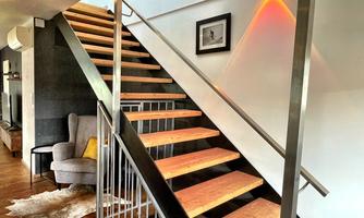 A modern staircase made of wood with an elegant railing. The space is bright and designed in a minimalist style.