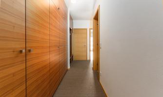 A bright hallway with wooden cupboards and a door at the end. The walls are painted in neutral colors.