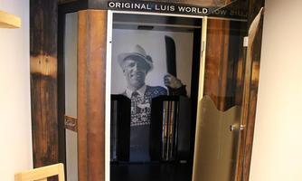 An old phone booth with a historic image in the background. The booth bears the inscription "Original Luis World".