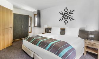 A modern bedroom with two beds, a large closet, and a stylish wall design. The color scheme is bright and inviting, perfect for a comfortable stay.