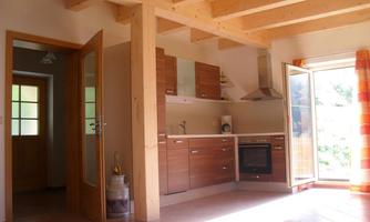 A modern kitchen with wooden shelves and bright tiles. The window is wide open, bringing in plenty of daylight.
