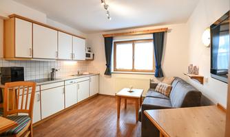 A cozy eat-in kitchen with bright furniture and a window. The room is well-lit and has a modern, inviting style.