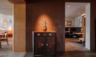 A stylish interior with an antique dresser and a decorative vase. In the background, tables and chairs can be seen in an inviting dining area.