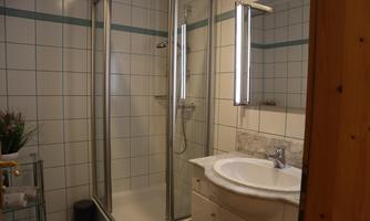 A modern bathroom with a shower and a sink. Bright tiles and pleasant lighting create a friendly atmosphere.
