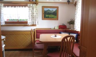 A cozy kitchen with a round table and red chairs. Bright walls and a window provide plenty of daylight.