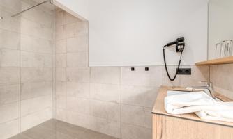 A modern bathroom with a spacious shower and a wooden vanity. Clean towels are ready, and the walls are painted in neutral colors.