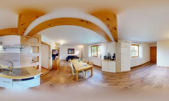 A modern living room with an open kitchen and wooden ceilings.  
Bright colors and a large window front create an inviting atmosphere.
