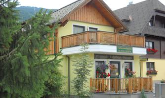 A charming house with a wooden balcony and colorful flowers.  
Surrounded by trees and located in a quiet setting.
