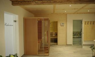 A modern wellness area with a wooden sauna and a relaxed atmosphere. The walls are light and the floor is made of stone.