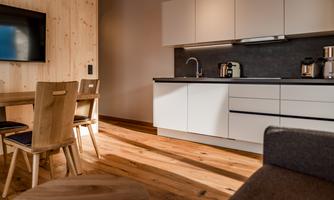 A modern kitchen with white cabinets and wooden details. The space has a warm, inviting charm with a wooden dining area.