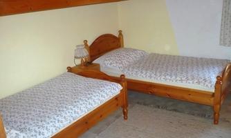 A simple bedroom with two wooden bed frames. The beds are decorated with patterned bedding and pillows.